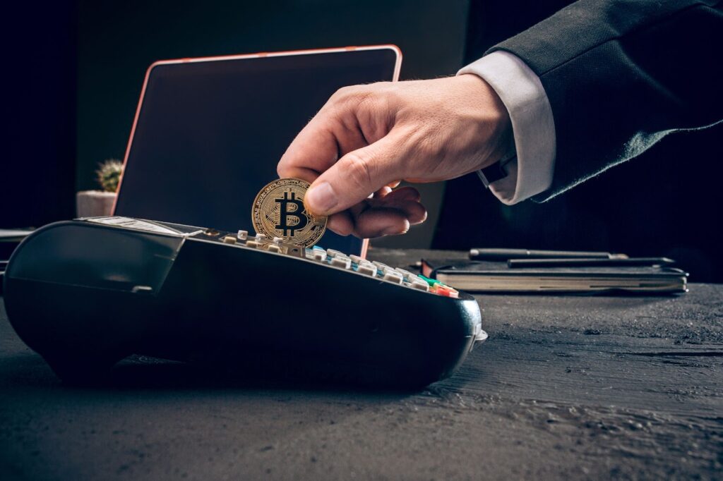 Photo of man holding bitcoin near pos-terminal