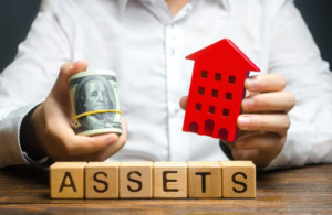 Man holding red house and roll of dollars over word "assets"